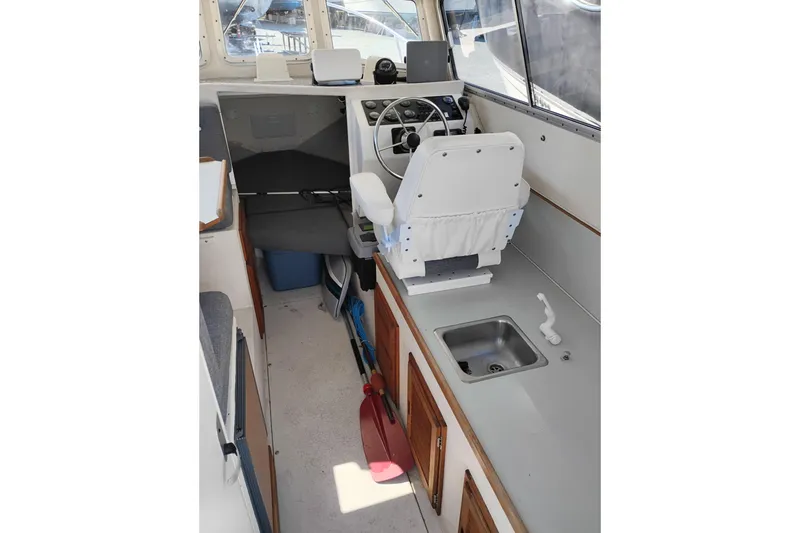 Slide: The Image of Interior of a 1997 SeaSport Explorer 2400 boat, featuring helm and compact kitchenette. - 17