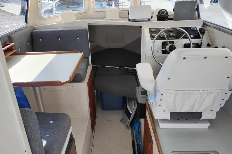 Slide: The Image of Interior of a 1997 SeaSport Explorer 2400 boat, featuring helm and seating area. - 25
