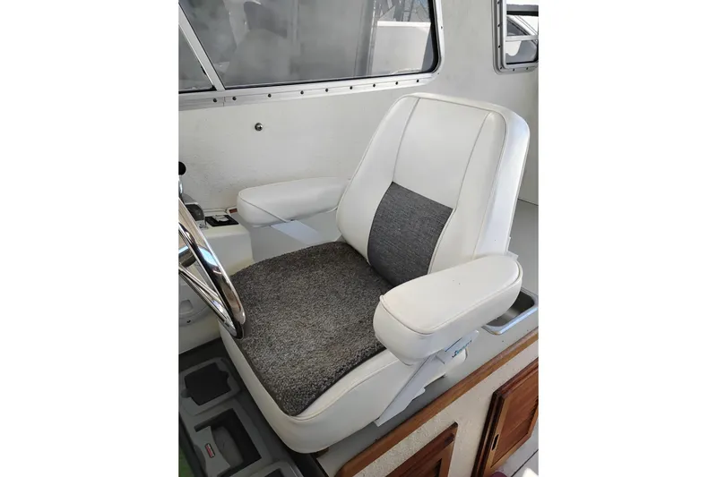 Slide: The Image of Captain's chair in 1997 SeaSport Explorer 2400 boat, featuring white and gray upholstery. - 26