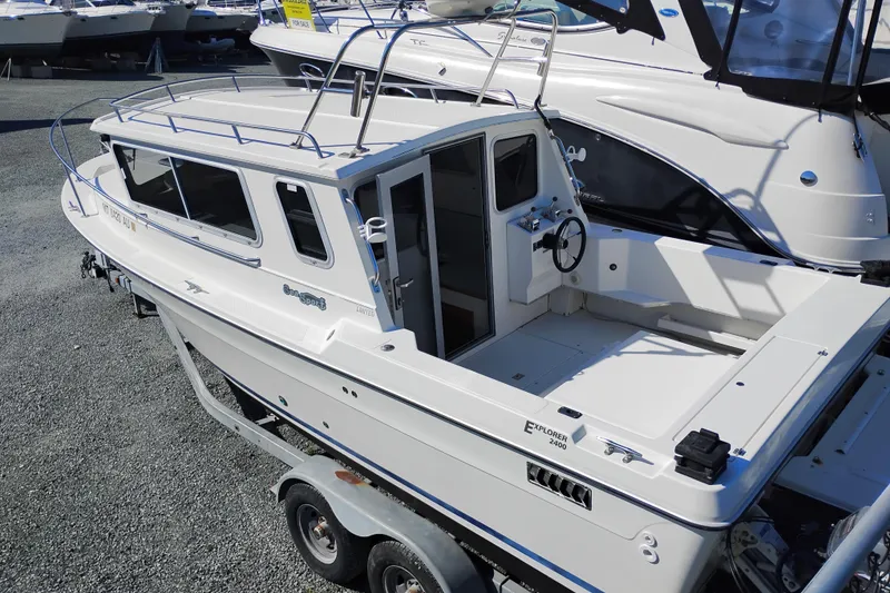 Slide: The Image of 1997 SeaSport Explorer 2400 boat on trailer, parked in a marina. - 4