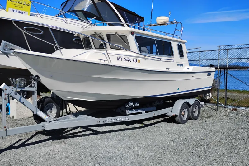 The Image of 1997 SeaSport Explorer 2400 boat on trailer, parked near waterfront, for sale. - 0