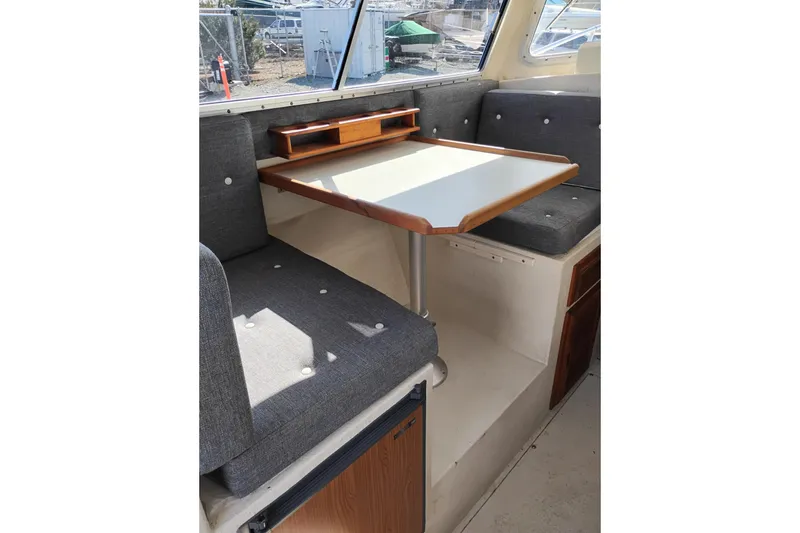 Slide: The Image of 1997 SeaSport Explorer 2400 interior with gray seating and wooden table. - 18
