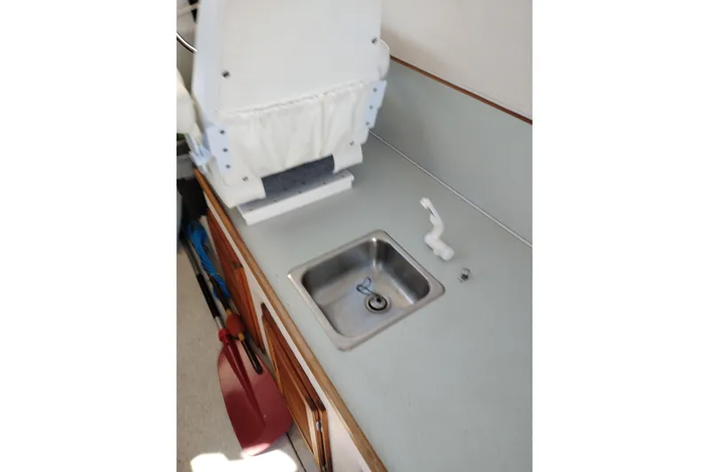 Slide: The Image of Interior of a 1997 SeaSport Explorer 2400 boat featuring a compact sink and countertop. - 21