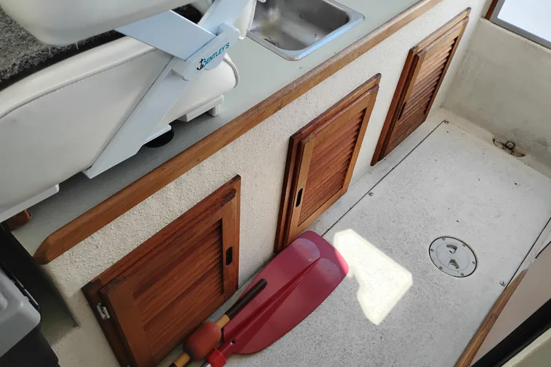 Slide: The Image of Interior of a 1997 SeaSport Explorer 2400 boat with wooden cabinets and red paddles. - 24
