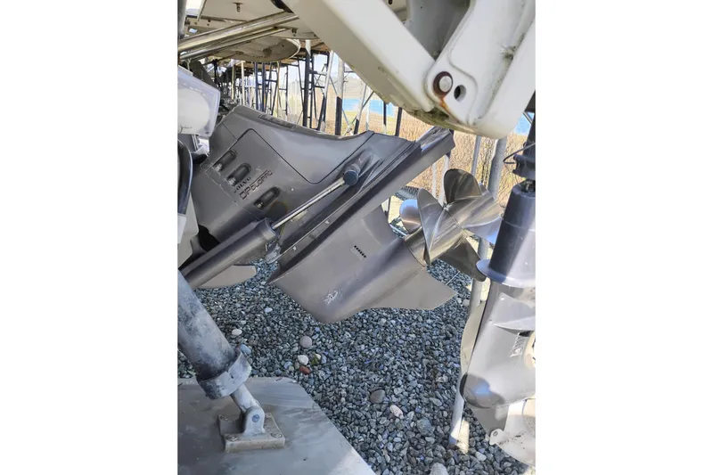 Slide: The Image of 1997 SeaSport Explorer 2400 boat propeller and outdrive on gravel surface. - 38