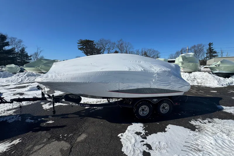 The Image of Covered 2023 Tahoe 1950 boat on trailer in snowy parking lot. - 1