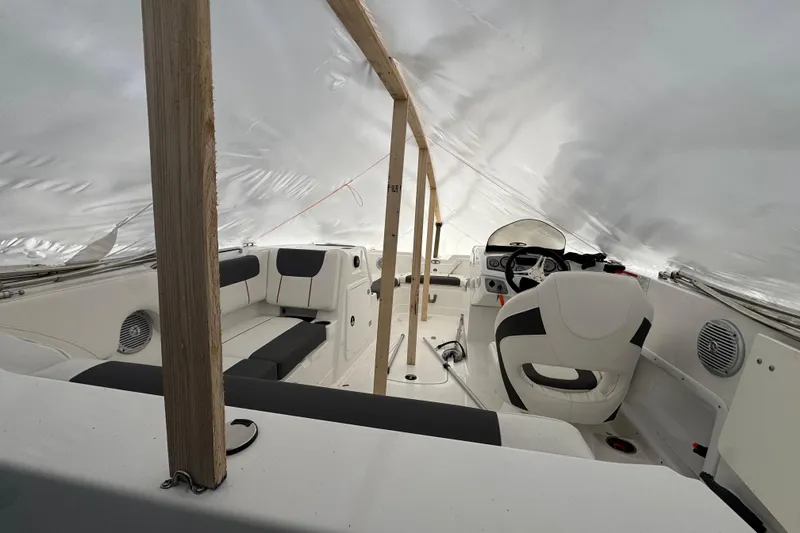 Slide: The Image of Interior of a 2023 Tahoe 1950 boat under protective cover, showcasing seating and steering area. - 8