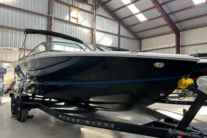 Slide: The Image of 2026 Four Winns H2 boat in a warehouse, sleek black design on a trailer. - 13