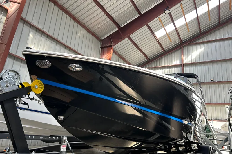 Slide: The Image of 2026 Four Winns H2 boat in a warehouse, black hull with blue stripe. - 15