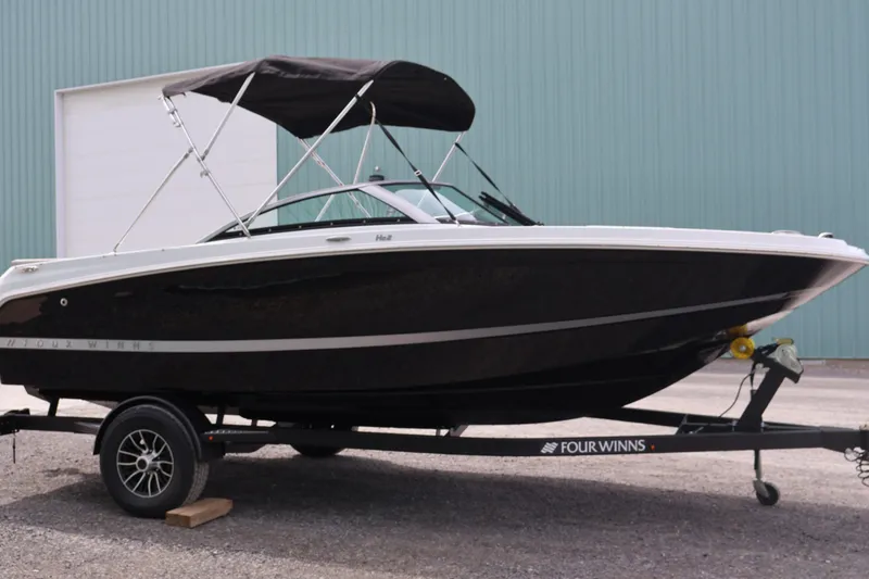 Slide: The Image of 2026 Four Winns HD2 boat on trailer, black hull, parked outdoors. - 29