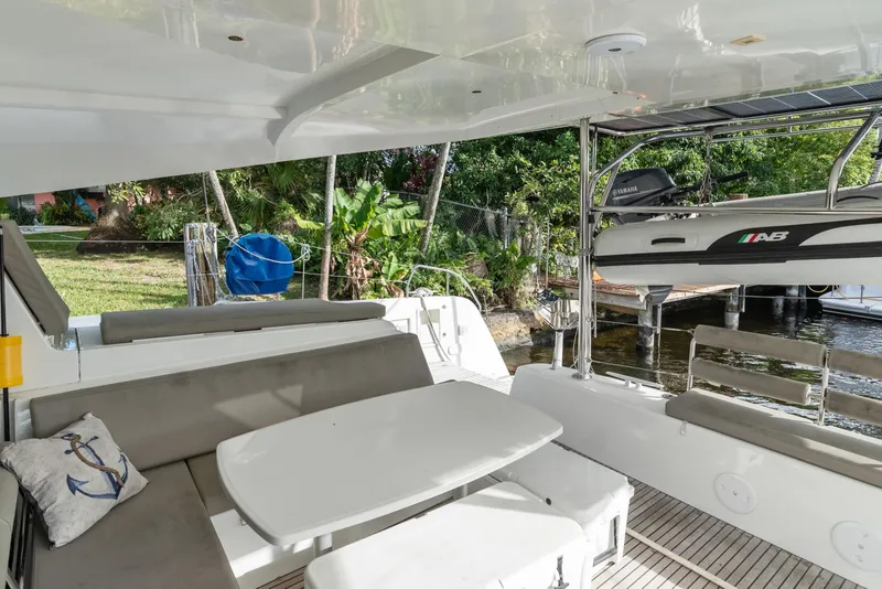 Slide: The Image of Outdoor seating area on a 2020 Lagoon 42 catamaran, featuring a table and lush surroundings. - 12