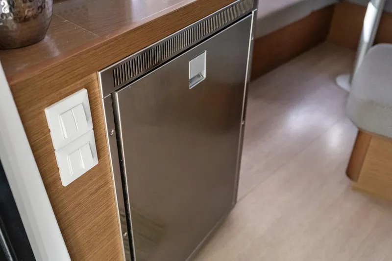 Slide: The Image of Interior of 2020 Lagoon 42 yacht featuring a stainless steel fridge and wooden cabinetry. - 14