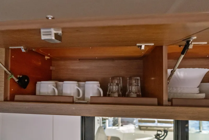 Slide: The Image of Open cabinet in Lagoon 42 yacht with mugs, glasses, and plates neatly arranged. - 19