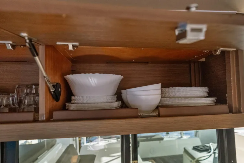 Slide: The Image of Cabinet in Lagoon 42 yacht with neatly stacked white dishes and glasses. - 20
