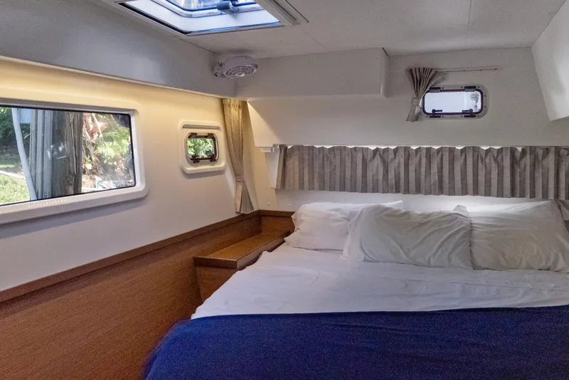 Slide: The Image of Cozy cabin interior of 2020 Lagoon 42 catamaran with bed and windows. - 26