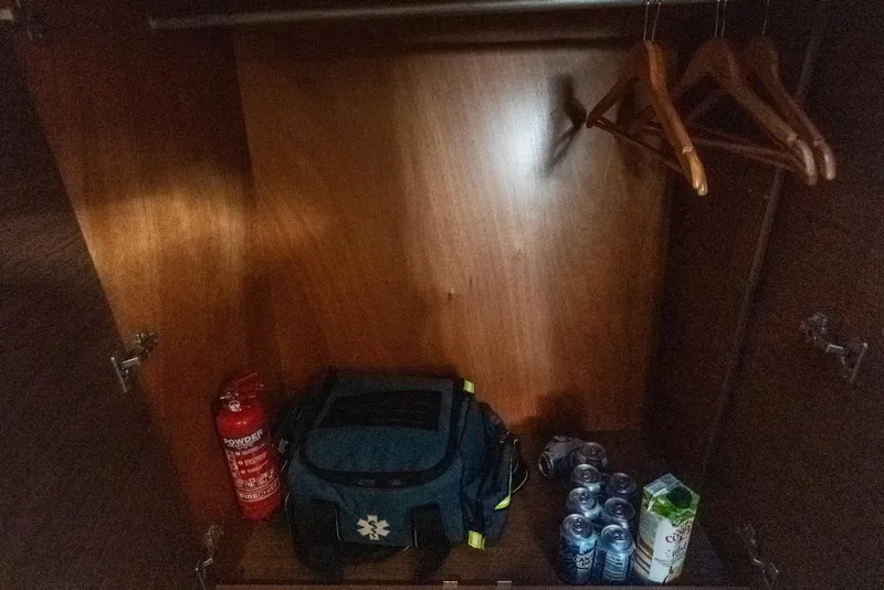 Slide: The Image of Wooden closet in Lagoon 42 yacht with fire extinguisher, bag, drinks, and hangers. - 31