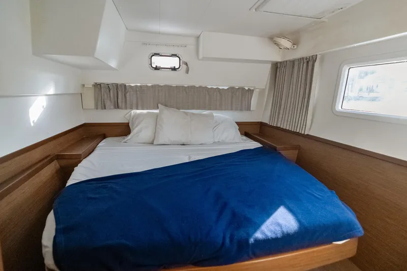 Slide: The Image of Cozy cabin interior of 2020 Lagoon 42 catamaran with bed and porthole window. - 32