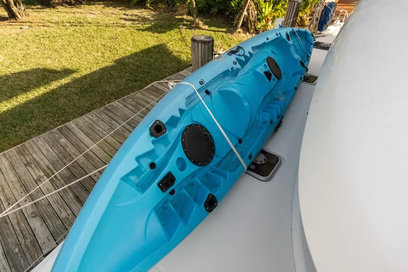 Slide: The Image of Blue kayak secured on Lagoon 42 catamaran deck, 2020 model, near wooden dock. - 4