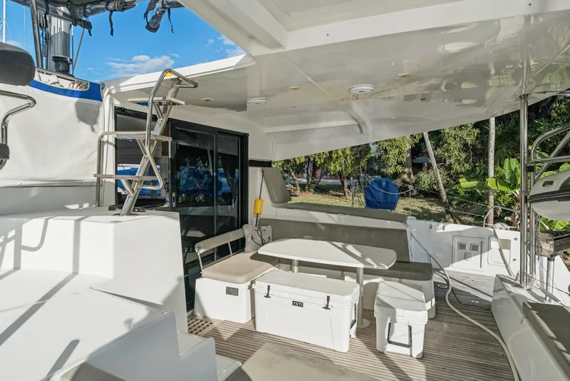 Slide: The Image of 2020 Lagoon 42 yacht deck with seating, table, and storage, surrounded by lush greenery. - 7