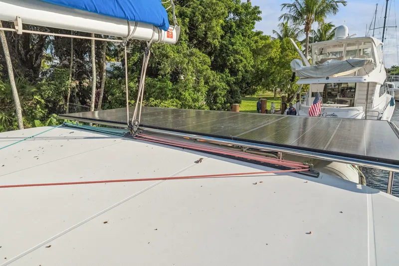 Slide: The Image of 2020 Lagoon 42 catamaran with solar panels, docked near lush greenery and another yacht. - 8