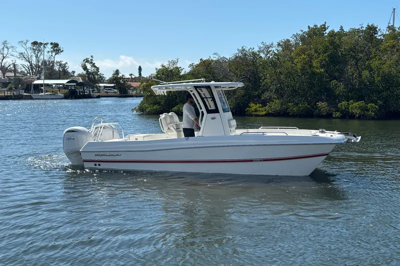 Slide: The Image of 2026 World Cat 235 TE boat cruising on a calm river with lush greenery. - 1