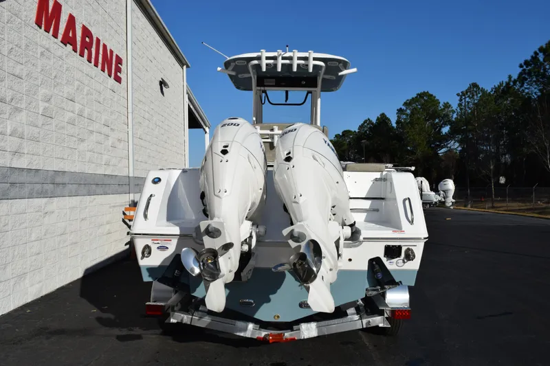 Slide: The Image of 2026 Sea Hunt Gamefish 25 boat with dual outboard engines, parked near a marine building. - 5