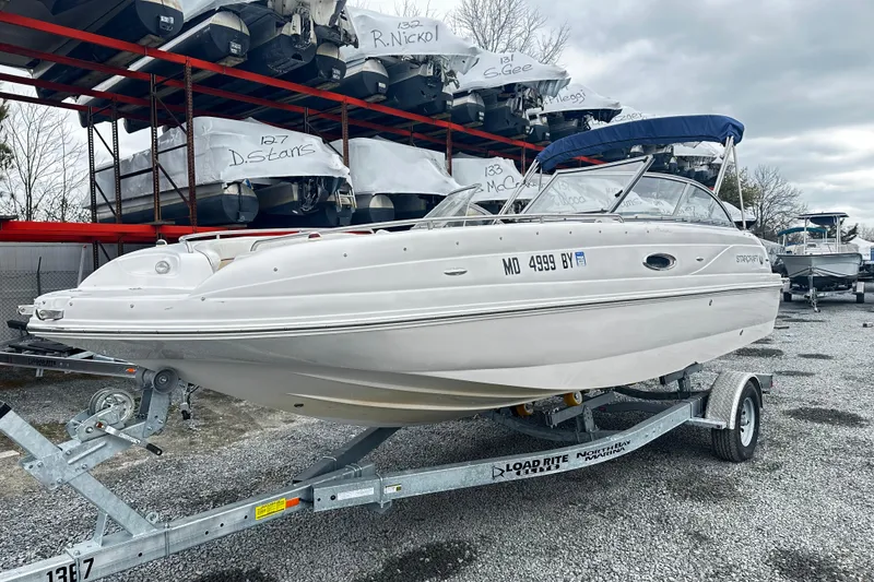 The Image of 2005 Starcraft Aurora 2210 OB boat on trailer, parked in a marina storage area. - 1
