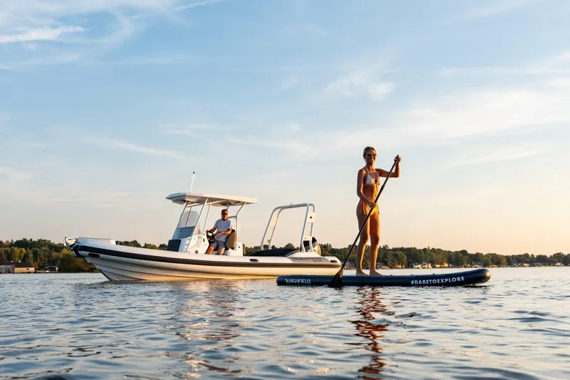 Slide: The Image of 2026 Highfield Escape 750 boat with paddleboarder on calm water at sunset. - 9