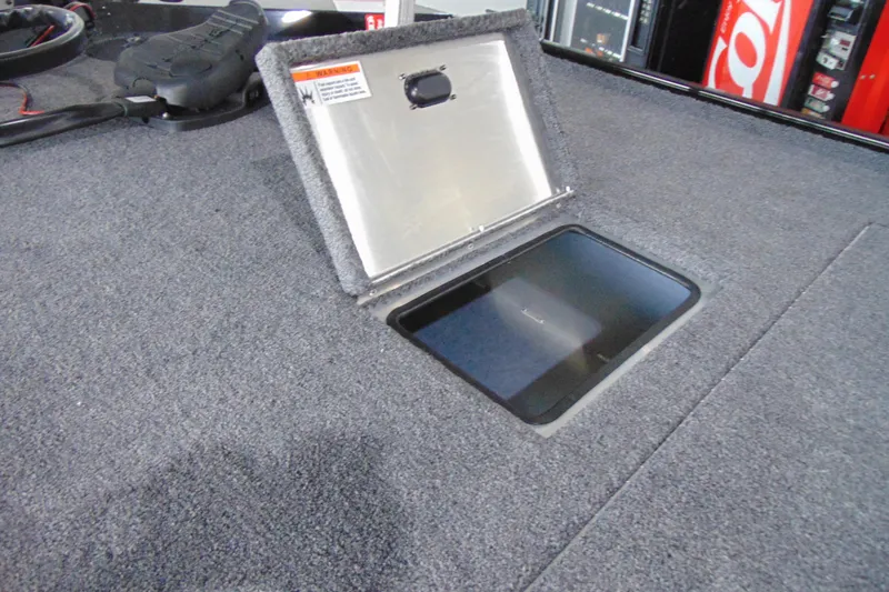 Slide: The Image of 2026 Crestliner 1600 Storm boat storage compartment with open hatch on carpeted deck. - 8
