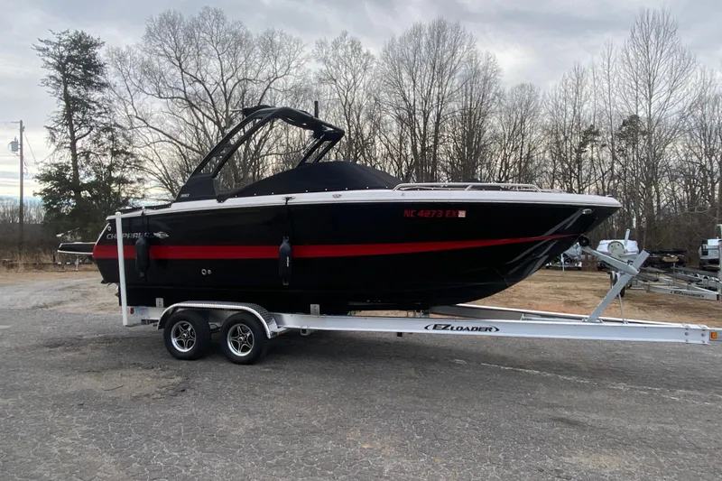 Slide: The Image of 2022 Chaparral 247 SSX boat on trailer, parked outdoors with trees in background. - 1