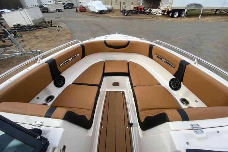 Slide: The Image of 2022 Chaparral 247 SSX boat interior with tan and black seating, cup holders, and speakers. - 2