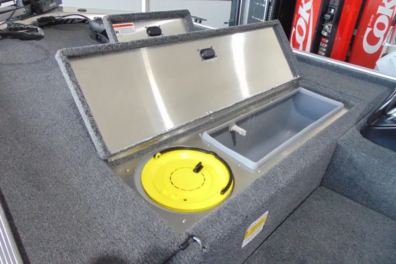 Slide: The Image of 2026 Crestliner 1600 Storm boat storage compartment with open lid and yellow container. - 7