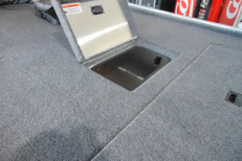 Slide: The Image of 2026 Crestliner 1600 Storm boat storage compartment with open hatch, carpeted interior. - 8