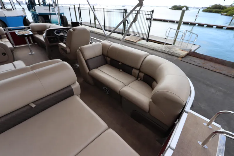 Slide: The Image of 2024 Sun Tracker Party Barge 22 DLX interior with beige seating and waterfront view. - 11
