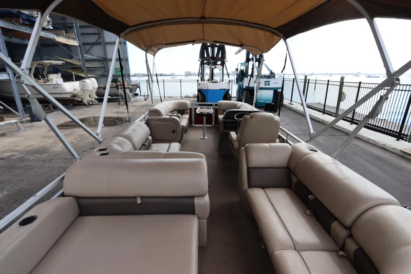Slide: The Image of 2024 Sun Tracker Party Barge 22 DLX with spacious seating and canopy, docked by the water. - 13