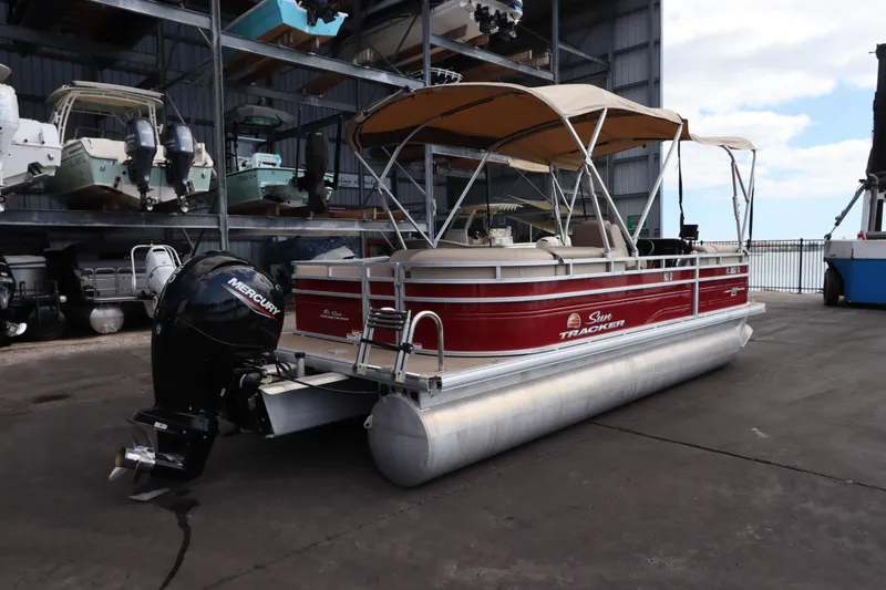 Slide: The Image of 2024 Sun Tracker Party Barge 22 DLX pontoon boat with Mercury outboard motor in storage facility. - 4