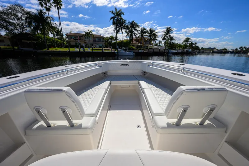 Slide: The Image of 2021 Invincible 39 Open Fisherman boat interior with white seating, docked by palm trees. - 32