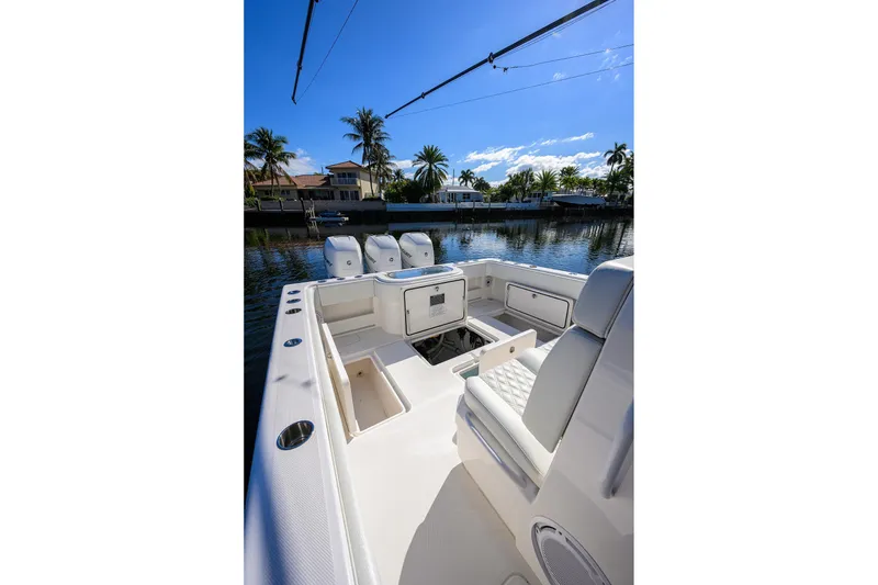 Slide: The Image of 2021 Invincible 39 Open Fisherman boat interior with seating and storage, docked by palm trees. - 58