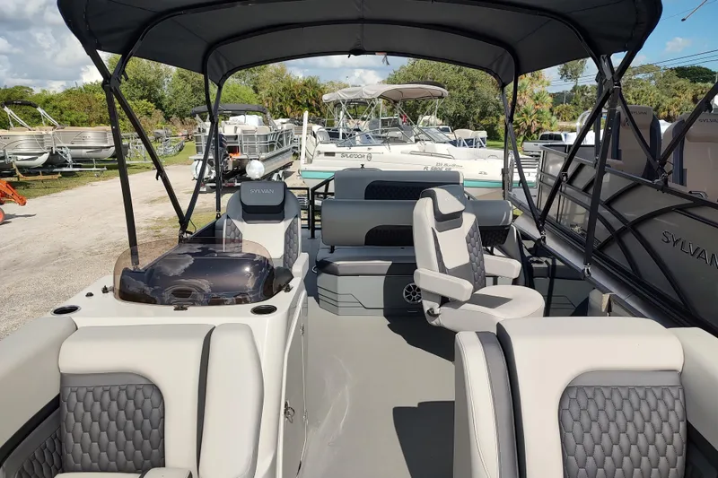 Slide: The Image of 2026 Sylvan L3 DLZ pontoon boat interior with seating and table, featuring cup holders. - 12