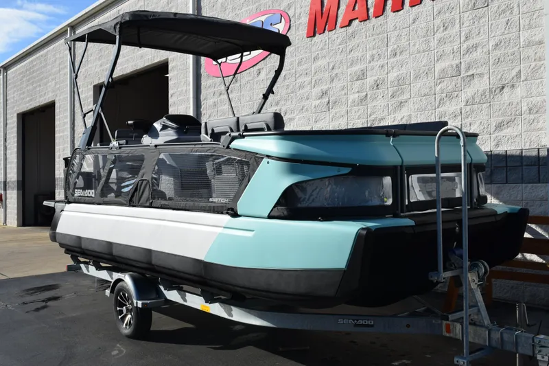 Slide: The Image of 2026 Sea-Doo Switch Cruise 21 pontoon boat on trailer, parked outside a building. - 2