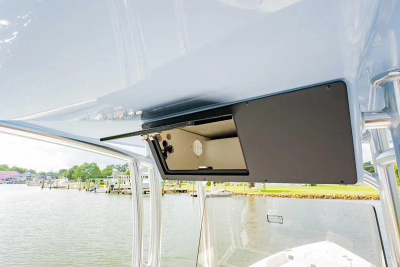 Slide: The Image of 2026 Bay Rider 219 Bay boat console with open storage compartment, dockside view. - 18