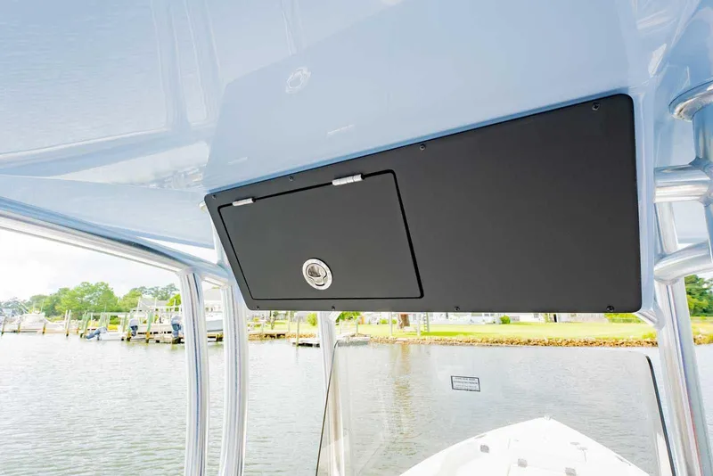 Slide: The Image of 2026 Bay Rider 219 Bay boat console with storage compartment, docked by a scenic waterfront. - 19