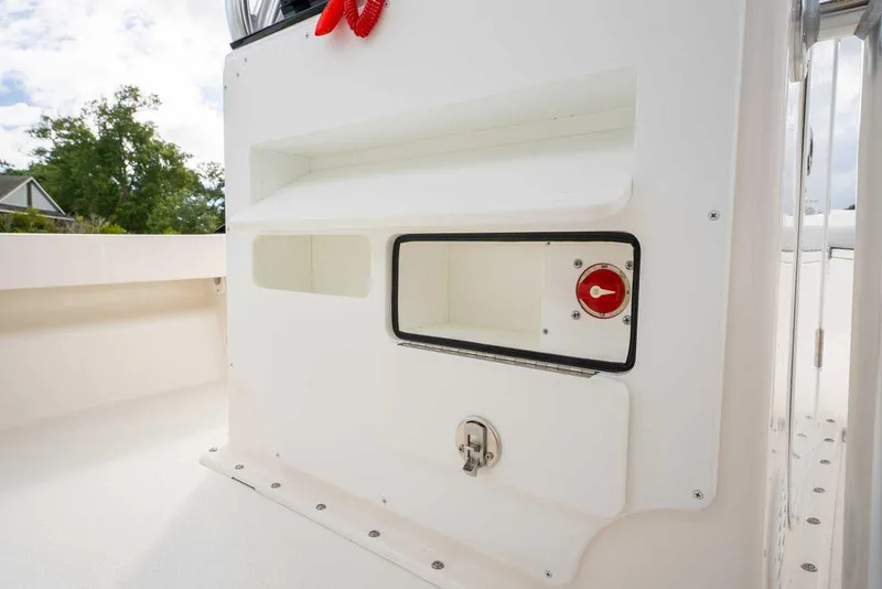 Slide: The Image of 2026 Bay Rider 219 Bay boat interior storage compartment with latch and red valve. - 31