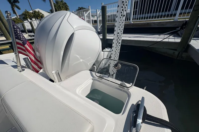 Slide: The Image of 2023 Edgewater 248CX Crossover boat interior with seating and console, docked by the water. - 20