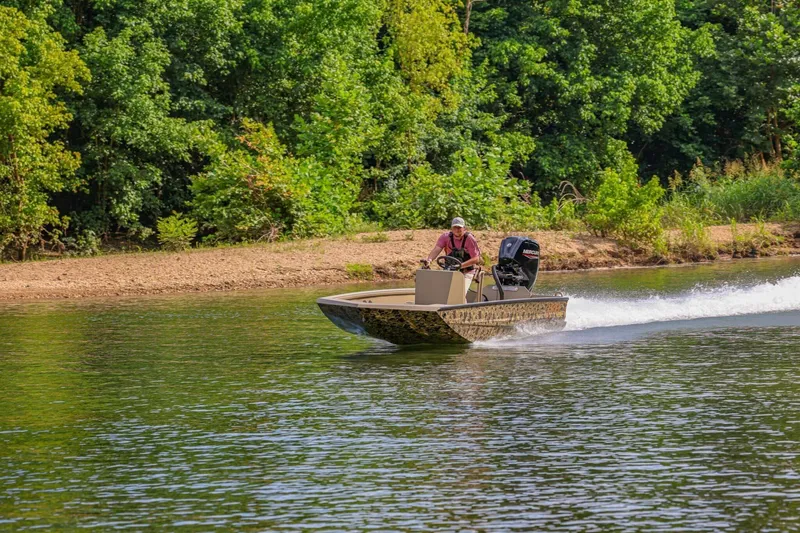 Slide: The Image of Man driving 2026 Excel Switchblade boat on a river with lush green trees. - 4
