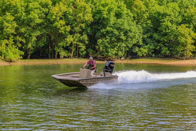 Slide: The Image of Man driving 2026 Excel Switchblade boat on a lake with lush green trees. - 5