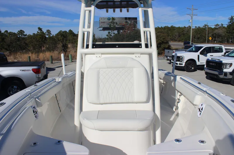 Slide: The Image of 2026 Key West 219 FS boat interior with white seating, parked near trucks. - 15