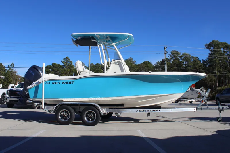 Slide: The Image of 2026 Key West 219 FS boat on trailer, vibrant blue hull, parked outdoors. - 4