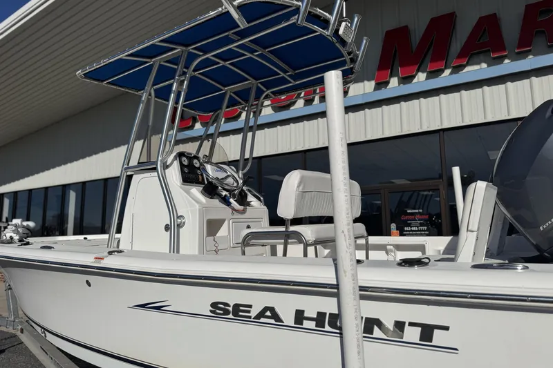 Slide: The Image of 2013 Sea Hunt BX 20 BR boat with T-top, parked outside a marine dealership. - 3