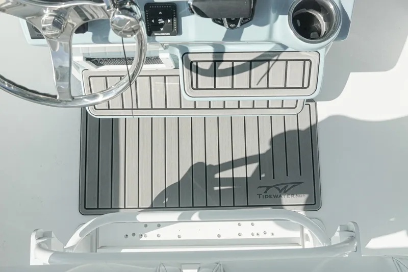 Slide: The Image of Steering area of 2026 Tidewater 232 CC Adventure boat with branded mat and controls. - 12